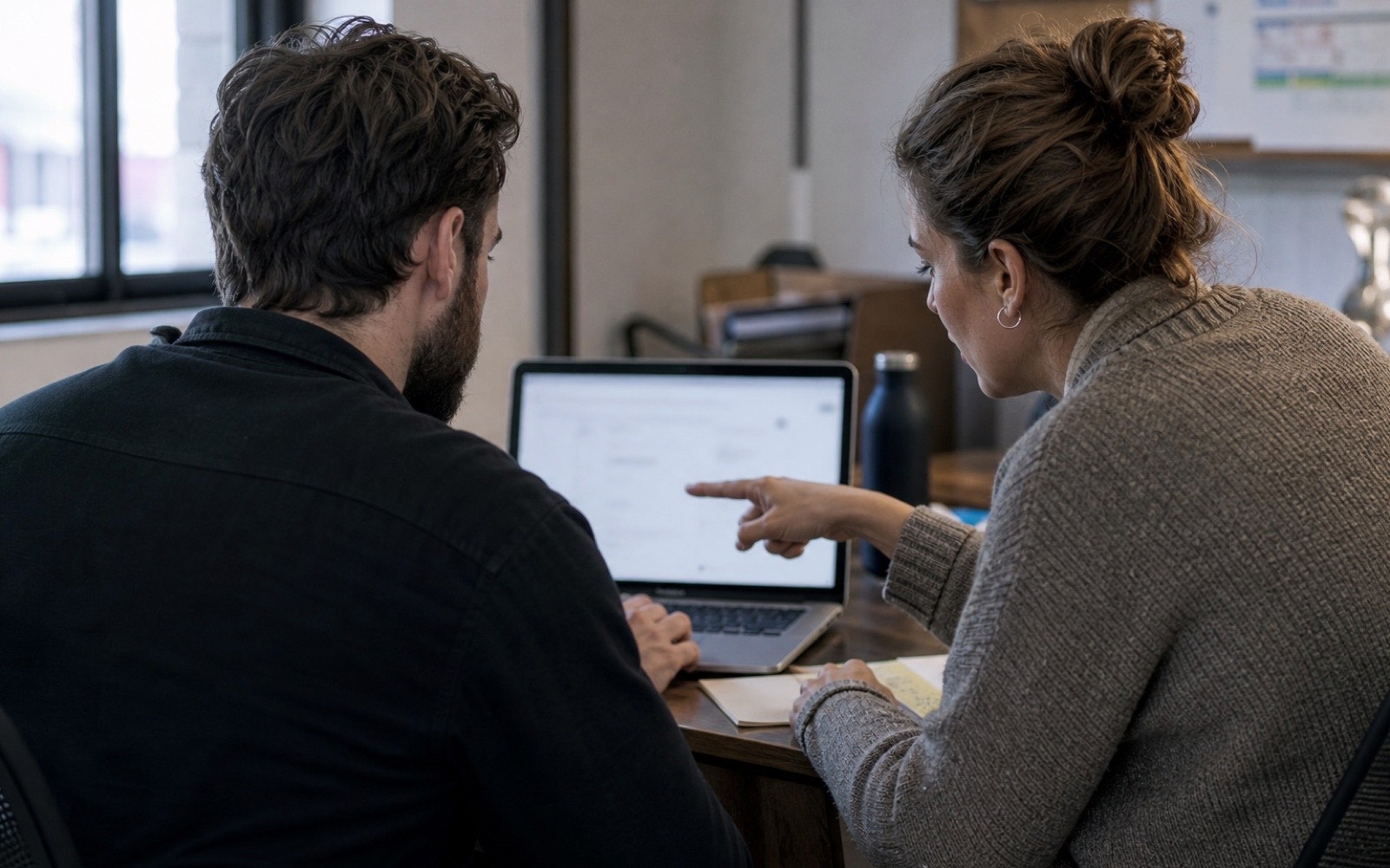 Two support colleagues review a customer case together at a desk, illustrating a human handoff with shared context.